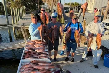 Group of people displaying a large catch of fish on a dock.