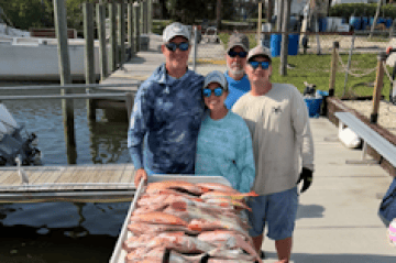 Four people behind a table with various large fish displayed.