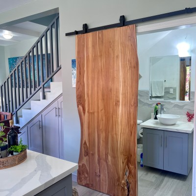 Interior with a sliding wooden door, staircase, and dining table with plants.