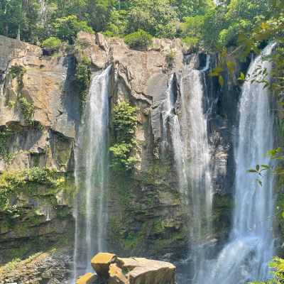 Three waterfalls cascading over rocky cliffs surrounded by lush greenery.
